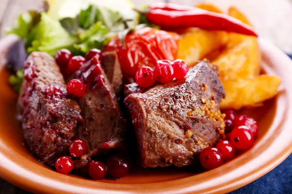 Вкусное жареное мясо с клюквенным соусом, салат и жареные овощи на тарелке, крупным планом — стоковое фото