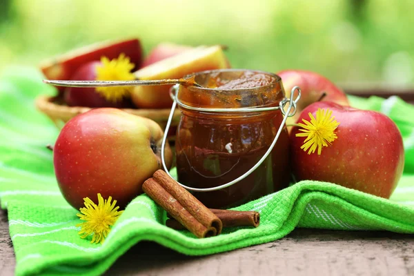 Apple jam in jar and fresh red apples outdoors — Stock Photo, Image