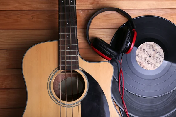 Гитара с виниловыми пластинками и наушниками на деревянном столе — стоковое фото