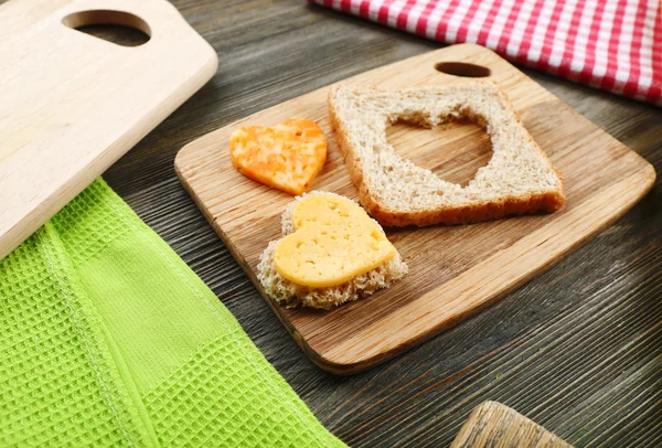 Bread slice with cut in shape of heart and cheese on table close up — Stock Photo, Image