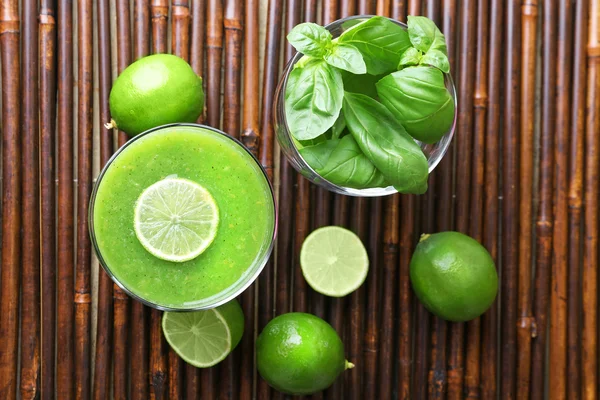 Glass of green healthy juice with basil and limes on table close up — Stock Photo, Image