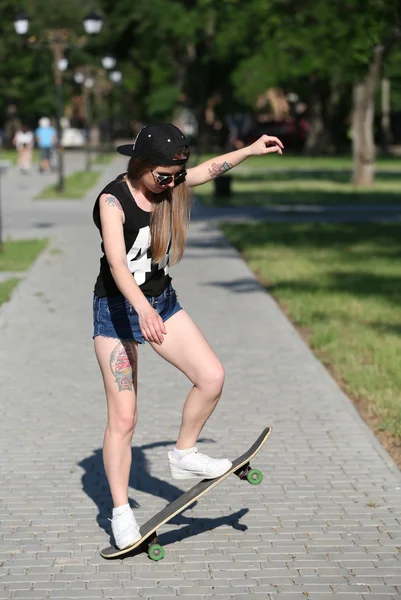 Mooi getatoeëerd meisje met skateboard — Stockfoto