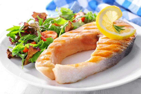 Salmão grelhado saboroso com salada na mesa de perto — Fotografia de Stock