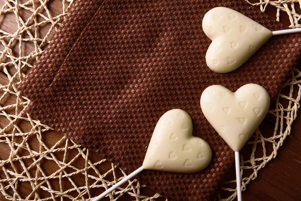 Caramelle a forma di cuore di cioccolato su bastoncini su tovagliolo marrone, primo piano — Foto Stock