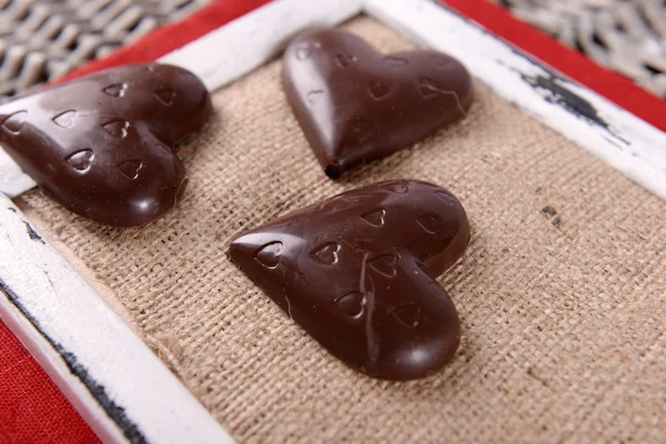 Шоколадные конфеты в форме сердца на палочках на раме с мешковиной, крупным планом — стоковое фото
