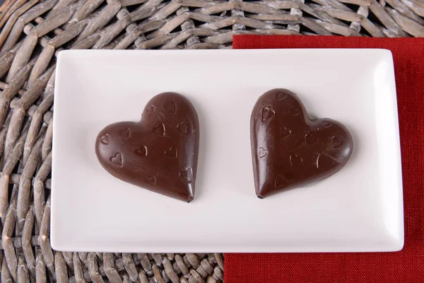 Doces em forma de coração de chocolate em paus em placa branca, close-up — Fotografia de Stock