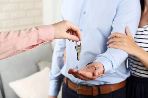 Agente imobiliário dando chaves para jovem casal — Fotografia de Stock
