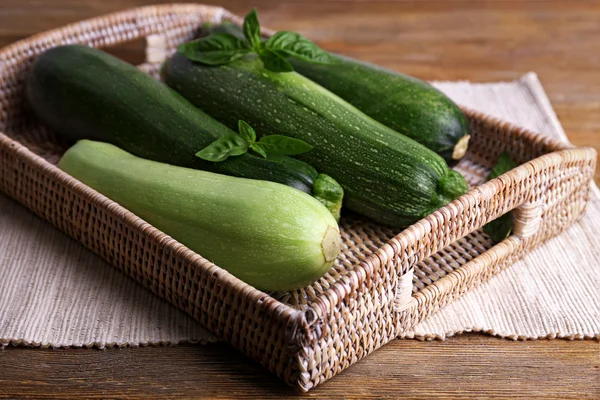 Cukety s squash a bazalkou na proutěný tác zblízka — Stock fotografie