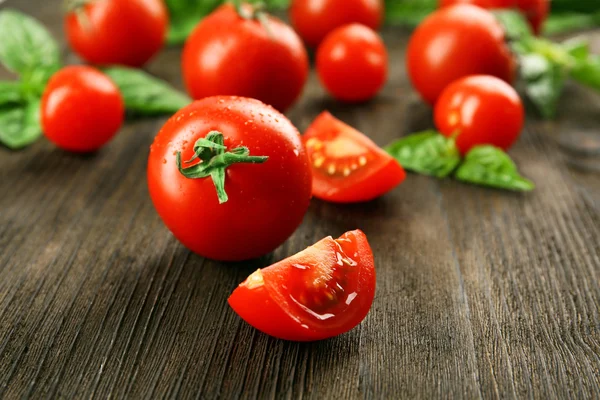 Tomates frescos con albahaca sobre mesa de madera de cerca —  Fotos de Stock