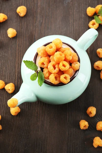 Yellow raspberries in teapot on wooden background — Stock Photo, Image