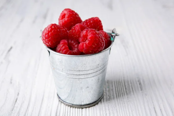 Fresh red raspberries in metal bucket on wooden background — Stock Photo, Image