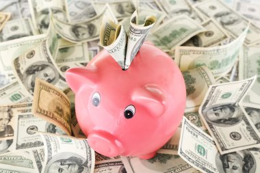 Piggy bank on pile of dollars clipart