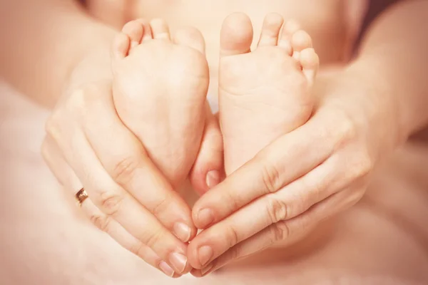 Newborn baby feet on female hands, close-up — Stock Photo, Image