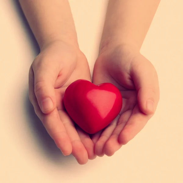 Corazón en manos de niños sobre fondo claro — Foto de Stock