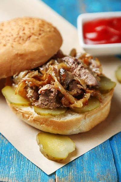 Gustoso panino su tovagliolo di carta, su sfondo tavolo di legno, primo piano concetto di cibo malsano — Foto Stock