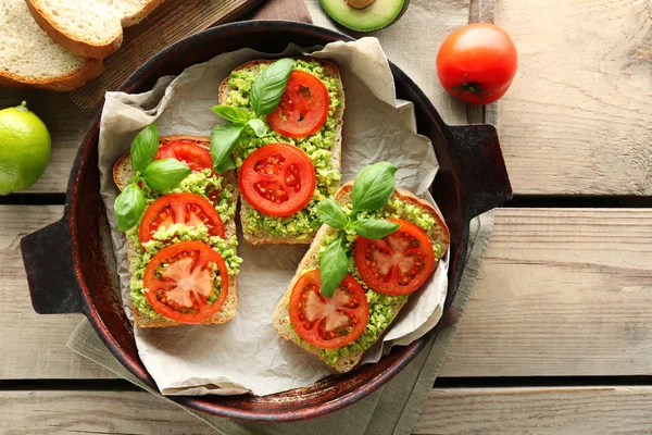 Sandwich vegano con aguacate y verduras en sartén, sobre fondo de madera —  Fotos de Stock