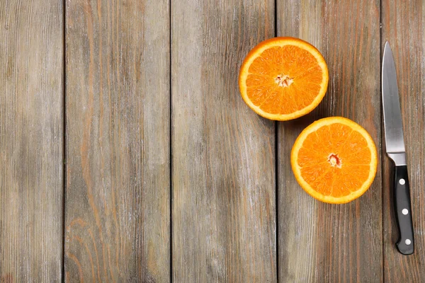 Mitades de naranja con cuchillo sobre fondo de madera —  Fotos de Stock