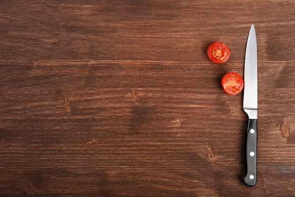 Halves of tomato with knife on wooden background — Stock Photo, Image