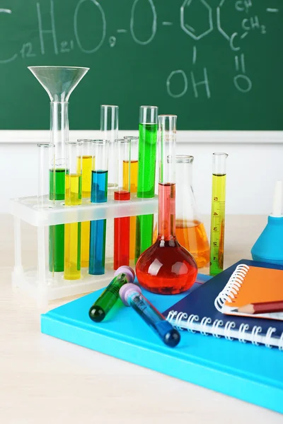 Desk in chemistry class with test tubes on green blackboard background