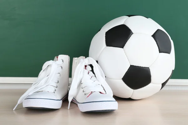 Scarpe sportive e pallone da calcio su sfondo lavagna — Foto Stock