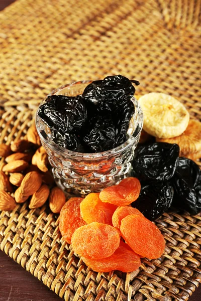 Prunes and other dried fruits on wicker mat, closeup — Stock Photo, Image