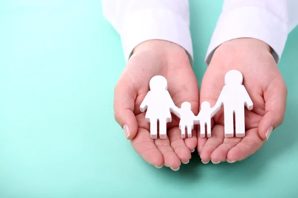 Mani femminili che tengono famiglia di giocattoli su sfondo di colore — Foto Stock