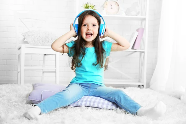 Beautiful little girl listening to music in room — Stock Photo, Image