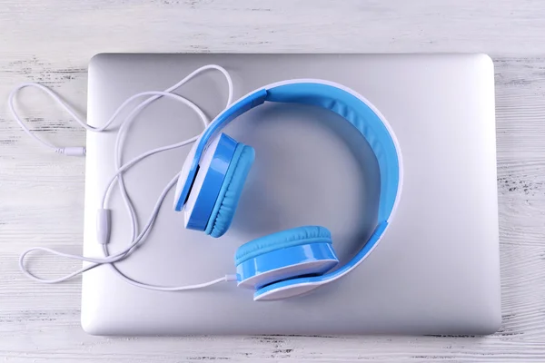 Fones de ouvido com laptop na mesa de perto — Fotografia de Stock