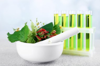 Harç, test tüpleri ve hapları, masada açık renkli otlar