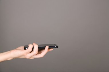 Cep telefonunuzun ve gri arka plan üzerinde el