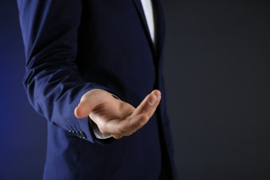 İş takım elbiseli adamı koyu arka plan üzerinde bir şey tanıtmak