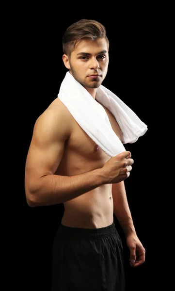 Muscle young man holding towel on dark background — Stock Photo, Image