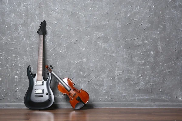 Guitarra elétrica e violino no fundo da parede cinza — Fotografia de Stock