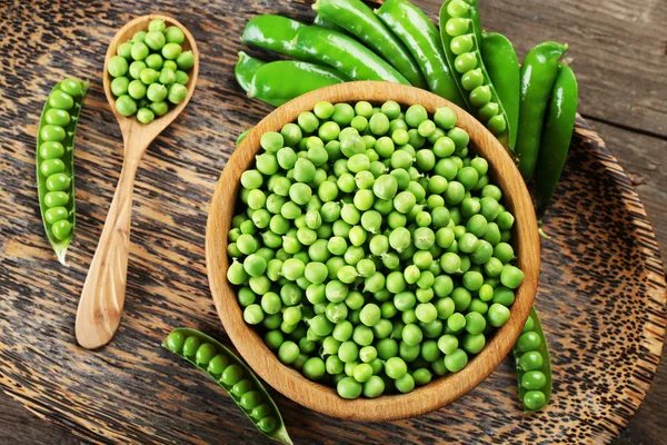 Fresh green peas in bowl on wooden tray, top view — Stock Photo, Image