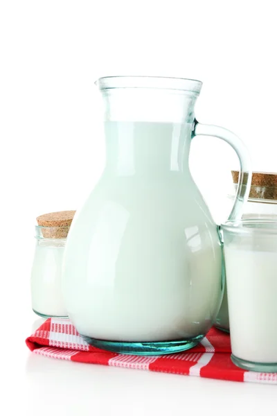 Кувшин и банки молока на деревянном столе, на белом фоне — стоковое фото