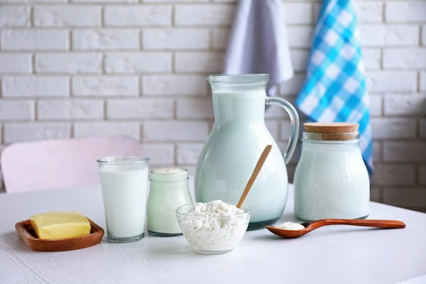 Молочные продукты на деревянном столе, на фоне кирпичной стены — стоковое фото