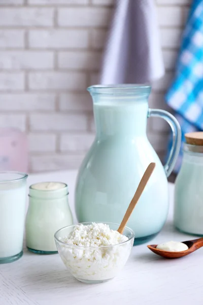 Dairy products on wooden table, on brick wall background — Stock Photo, Image