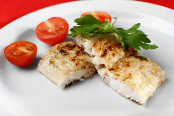 Dish of fish fillet with parsley and tomato on plate close up — Stock Photo, Image