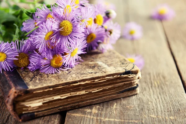 Παλιό βιβλίο με όμορφα λουλούδια σε ξύλινο τραπέζι από κοντά — Φωτογραφία Αρχείου