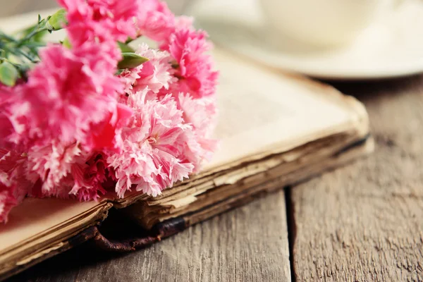 Livro velho com belas flores e xícara de chá na mesa de madeira close-up — Fotografia de Stock