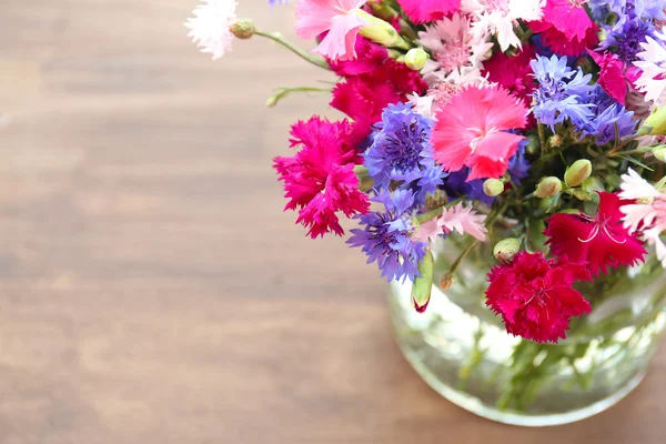 Schöne kleine Wildblumen in der Vase auf Holzgrund — Stockfoto