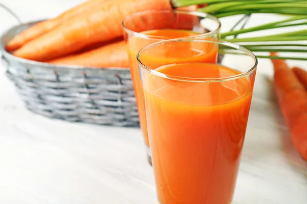 Se acercan los vasos del jugo de zanahoria con hortalizas a la mesa — Foto de Stock