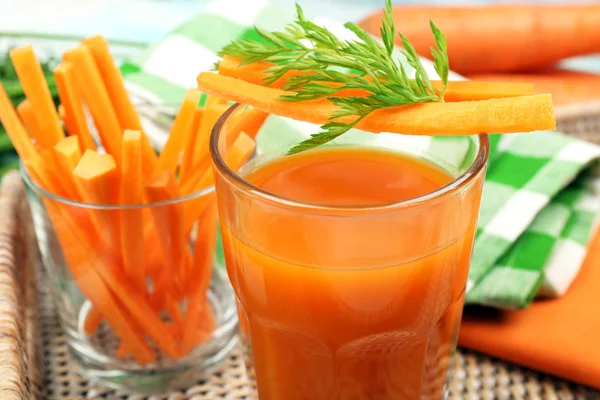 Glass of carrot juice with vegetable slices on table close up — Stock Photo, Image