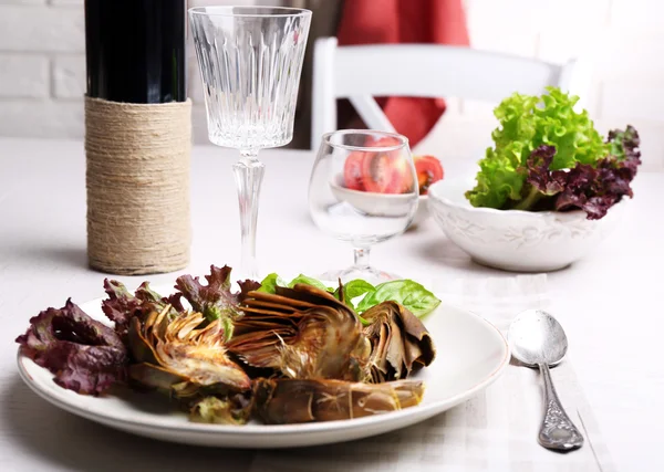 Roasted artichokes on plate, on kitchen table background — Stock Photo, Image