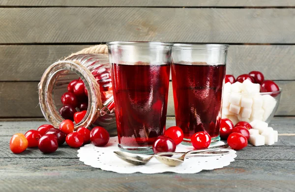 Glasses of sweet homemade cherry compote on table on wooden background — Stock Photo, Image