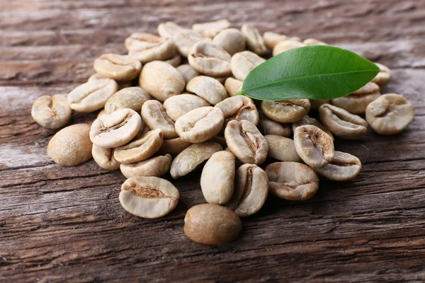 Hromadu zelené kávové boby na dřevěný stůl, detail — Stock fotografie