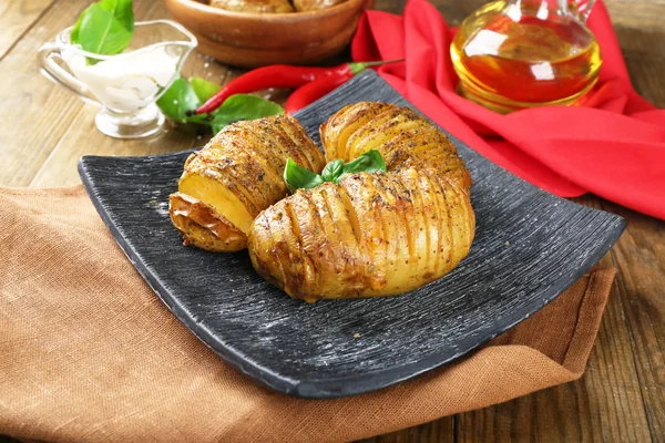 Baked potatoes with basil leaves on wooden table, closeup — Stock Photo, Image