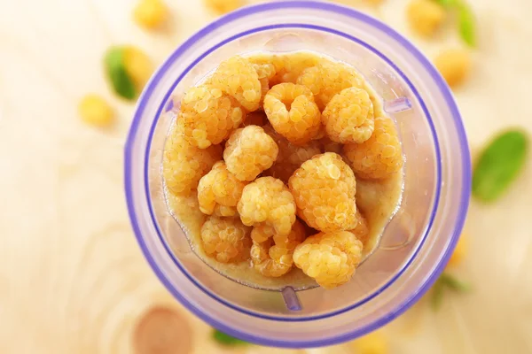 Yellow raspberries in blender cup on wooden table, closeup — Stock Photo, Image