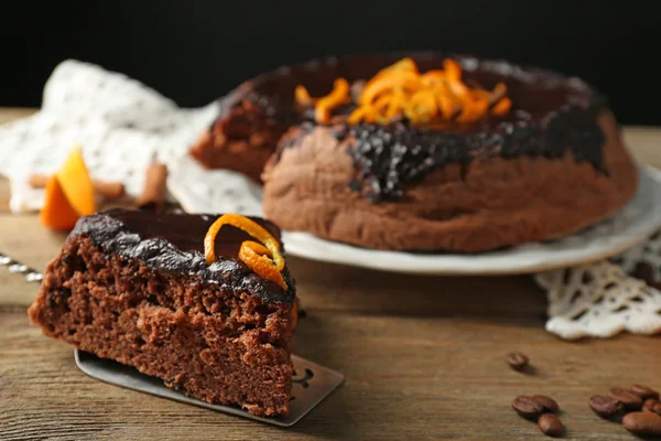 チョコレート艶出しと暗い背景に、木製のテーブルの上の皿にオレンジ ケーキ — ストック写真