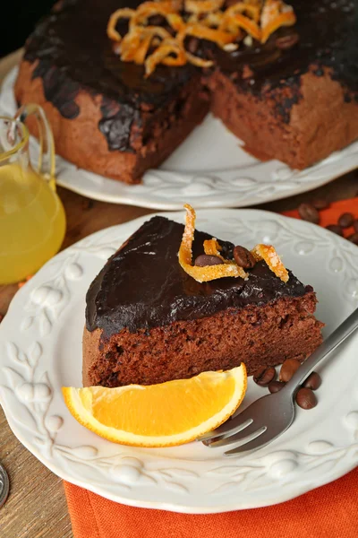 Cake met chocolade glazuur en oranje op plaat, op houten achtergrond — Stockfoto